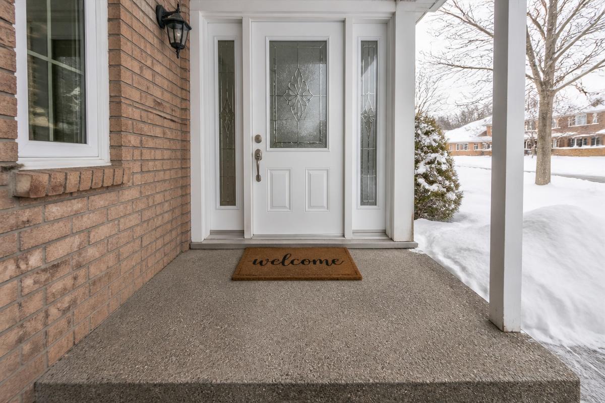 A cleared covered front entryway with a welcome mat and snow banks beyond